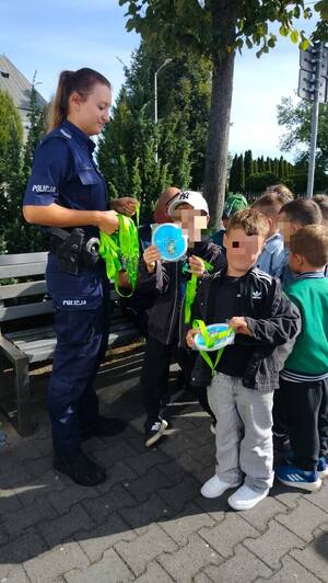 Policjanci rozdają odblaskowe gadżety dzieciom.
