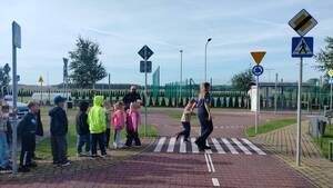 Policjanci z dziećmi w miasteczku ruchu drogowego.