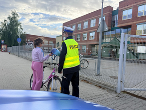 Policjant kontroluje dziewczynkę na rowerze.