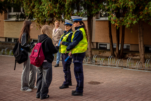 Policjantki ruchu drogowego rozdają elementy odblaskowe młodzieży.