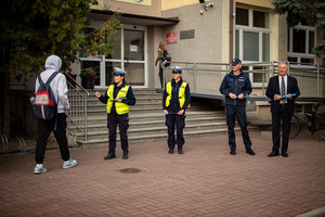 Policjanci ze starostą rozdają elementy odblaskowe.