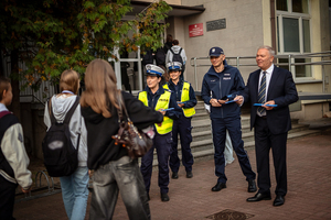 Policjanci ze starostą rozdają elementy odblaskowe.
