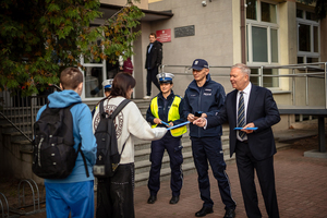 Policjanci ze starostą rozdają elementy odblaskowe.