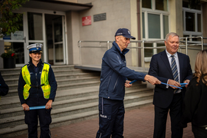 Policjanci ze starostą rozdają elementy odblaskowe.