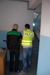 zatrzymany mężczyzna przy nim stoi policjant, zdjęcie zrobione w pomieszczeniu służbowym.
