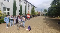 dzielnicowi z PP w Ruścu przygotowują dzieci ze SP w Woli wiązowej w powiecie bełchatowskim do egzaminu praktycznego na kartę rowerową. przed szkoła rozstawiony tor przeszkód rowerowy.