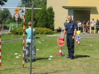 egzamin na kartę rowerową, uczeń na rowerze pokonuje tor przeszkód pod okiem policjanta