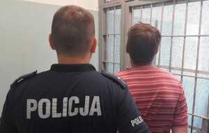 Poszukiwany listem gończym zatrzymany przez dzielnicowych. Policjant prowadzi zatrzymanego.